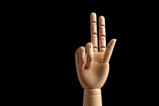 Дерев'яна рука манекена для малювання показує три пальці на чорному тлі. Вчимося рахувати - три. Вид збоку. Художня модель для малювання. Частина тіла - рука, пензель
. - Фото, зображення