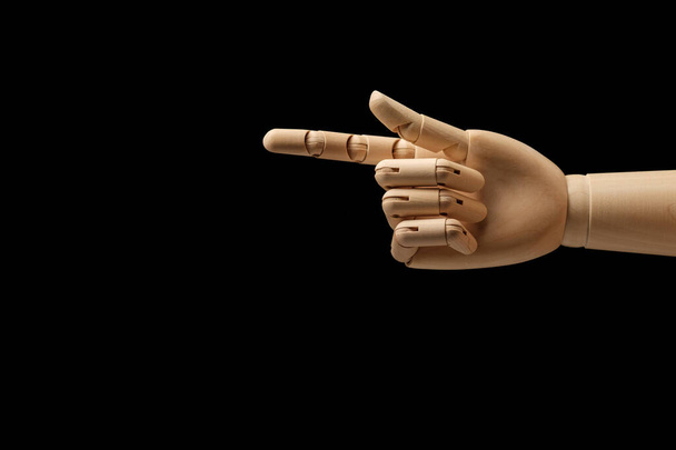 Деревянная рука манекена для рисования указывает направление указательного пальца на черном фоне. Указательный палец. Вид сбоку. Художественная модель для рисования. Часть тела - рука, кисть. - Фото, изображение