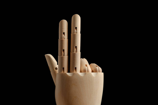 La mano de madera del maniquí para el dibujo muestra tres dedos sobre un fondo negro. Aprender a contar - tres. Vista lateral. Modelo de arte para el dibujo. Parte del cuerpo - mano, cepillo. - Foto, imagen