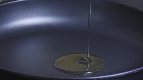 Slow motion  of  oil for cooking pouring into a frying pan. Cook pours sunflower oil into a frying pan, macro shot.  Olive oil is poured into a frying pan. - Video, Çekim