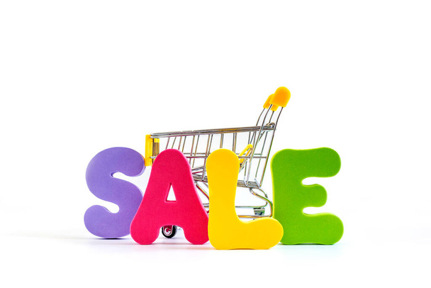 Word SALE written in bright colorful letters and Shopping cart isolated on white background. - Foto, afbeelding