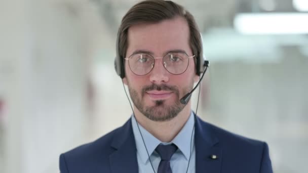 Fiatal üzletember portréja fejhallgatóval mosolygós arccal a kamera előtt  - Felvétel, videó