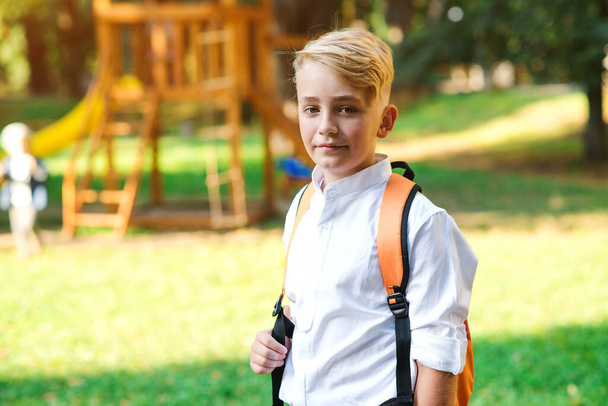Sırt çantalı yakışıklı çocuk okula gidiyor. Süslü beyaz gömlek giyen bir çocuk. Küçük moda, okul üniforması. Okul konseptine geri dönelim. Eğitim, insanlar ve yaşam tarzı. - Fotoğraf, Görsel