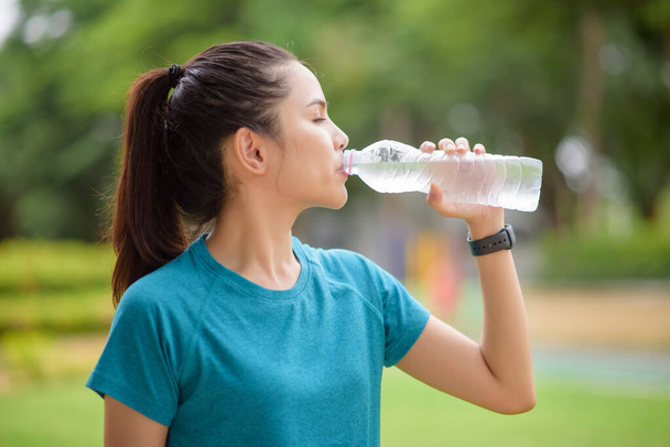 Fitness woman is drinking water after workout in park - Φωτογραφία, εικόνα