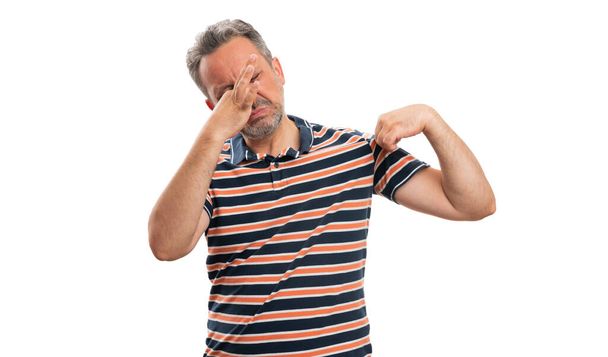 Erwachsenes männliches Modell mit grobem Gesichtsausdruck hält Nase als stinkende verschwitzte Achselhöhle Konzept trägt lässiges Sommer-T-Shirt isoliert auf weißem Studiohintergrund - Foto, Bild