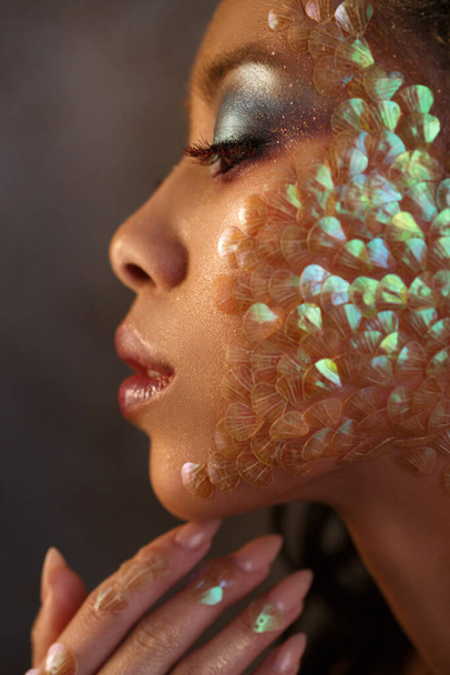 Beauty portrait of a beautiful Asian girl with creative make-up of a mermaid and scales on the face view in profile. - Foto, imagen