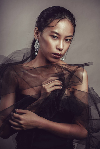 Beauty portrait of a beautiful asian girl with black transparent fabric. - Photo, image