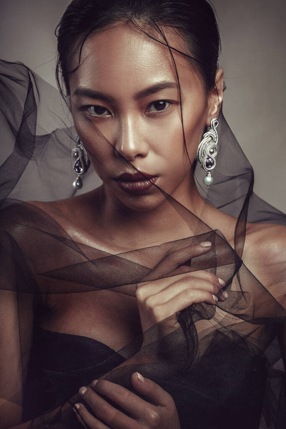 Beauty portrait of a beautiful asian girl with black transparent fabric. - Photo, image