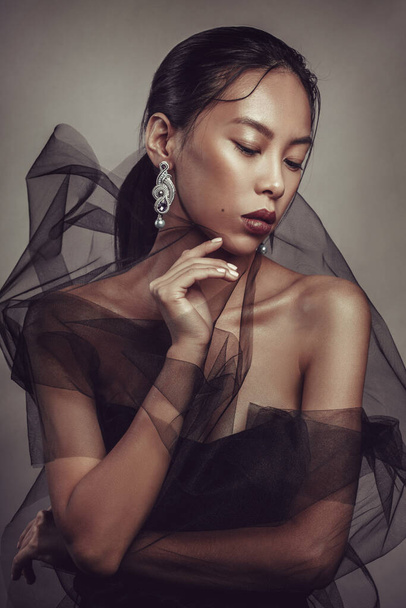 Beauty portrait of a beautiful asian girl with black transparent fabric. - Фото, изображение