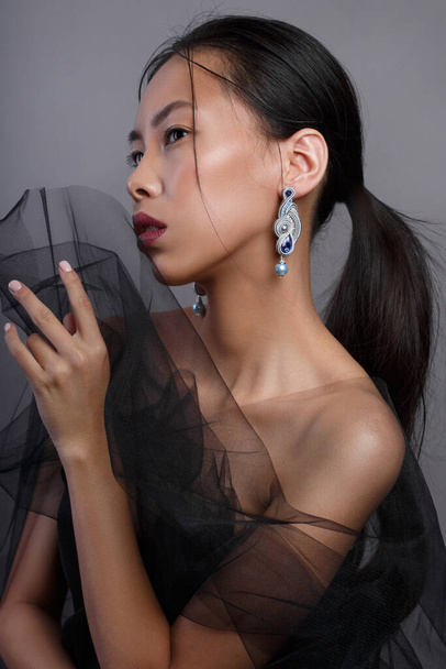 Beauty portrait of a beautiful asian girl with black transparent fabric. - Foto, imagen