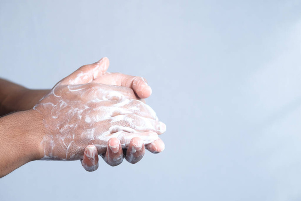 Nuori mies pesee kädet saippualla lämpimällä vedellä  - Valokuva, kuva