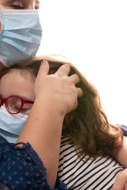 Nainen lohduttaa tyttö kärsii coronavirus naamio, halauksia koskettaa hänen hiukset - Valokuva, kuva