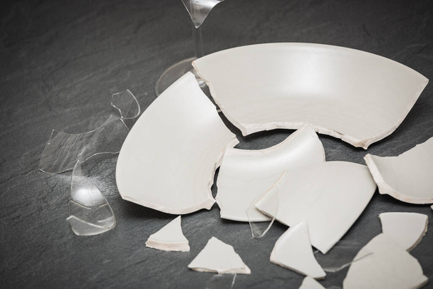 Σπασμένο πιάτο ή σπασμένα γυαλιά νερού στο πάτωμα της κουζίνας Η έννοια των ατυχημάτων στην κουζίνα είναι επικίνδυνη για το σώμα και τα μικρά παιδιά μέσα στο σπίτι. - Φωτογραφία, εικόνα