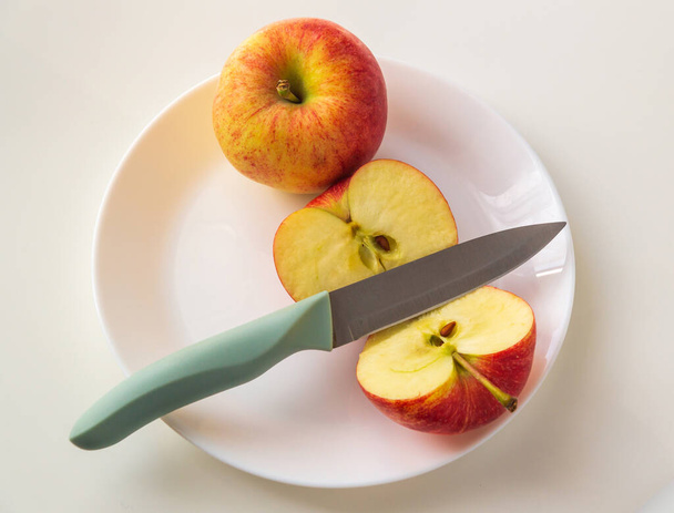 ナイフで皿の中に赤いリンゴを熟す。食事や断食の日に従うために食べる前にアップルをカット - 写真・画像