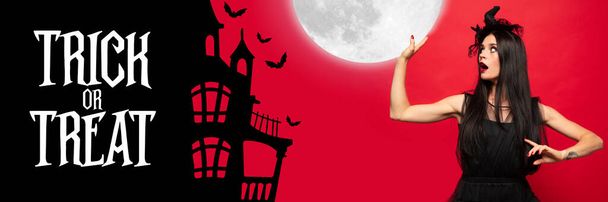 Young woman in hat as a witch on scary red background - Foto, imagen