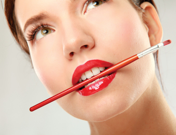 Woman's lips holding make up brush - Foto, Bild