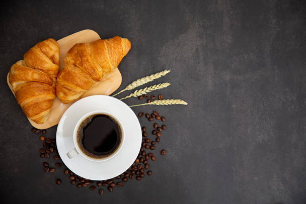 Café da manhã com xícara de café preto com pão com Croissant e frutas no fundo preto. - Foto, Imagem