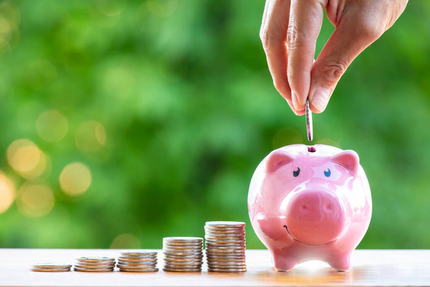Happy Pink Piggy  Bank in close-up and coins stack and Coin handle on the nature background, Saving ideas  and investment budget, Business saving money concept, Copy space - Φωτογραφία, εικόνα