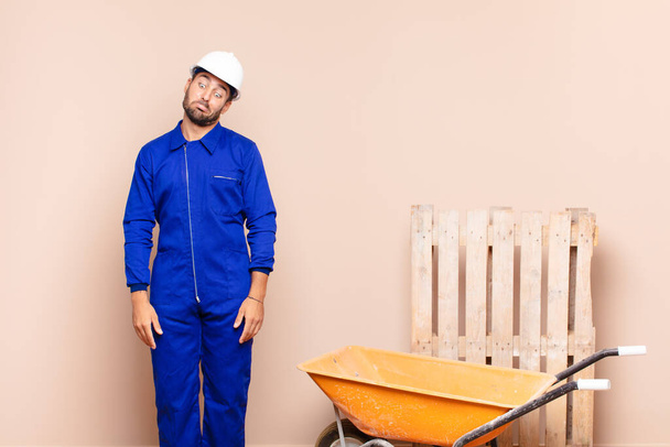 young man looking goofy and funny with a silly cross-eyed expression, joking and fooling around construction concept - Photo, Image