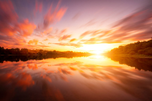 Coucher de soleil ou lever de soleil sur un lac ou une rivière avec un ciel nuageux se reflétant dans l'eau un soir ou un matin d'été. Paysage. - Photo, image