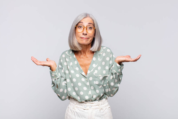 gray haired woman feeling puzzled and confused, doubting, weighting or choosing different options with funny expression - Foto, afbeelding