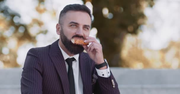 Ei ole aikaa lounaalle. Ulkona muotokuva liikemies syö pizzaa syksyllä puistossa - Materiaali, video