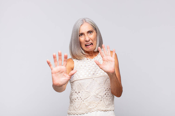 gray haired woman feeling terrified, backing off and screaming in horror and panic, reacting to a nightmare - 写真・画像