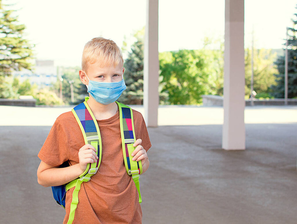 De vuelta a la escuela. Niño en edad escolar con una máscara médica protectora en su cara con una mochila escolar. Nuevo año escolar en 2020.C Equipos de protección individual - Foto, imagen