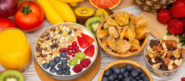 グループフルーツサラダボウル、ナッツボウル、ストロベリー、バナナ、パイナップルと混合野菜の朝食、オレンジジュース、健康と食事のための食品の性質のビタミンcは、木のテーブルの上のビューで. - 写真・画像