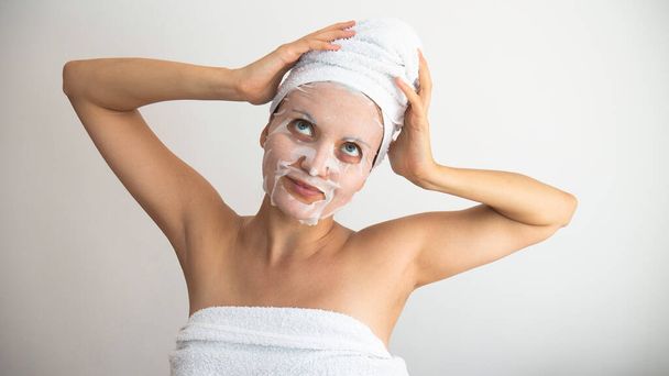 Femme avec un masque cosmétique blanc sur le visage.  - Photo, image
