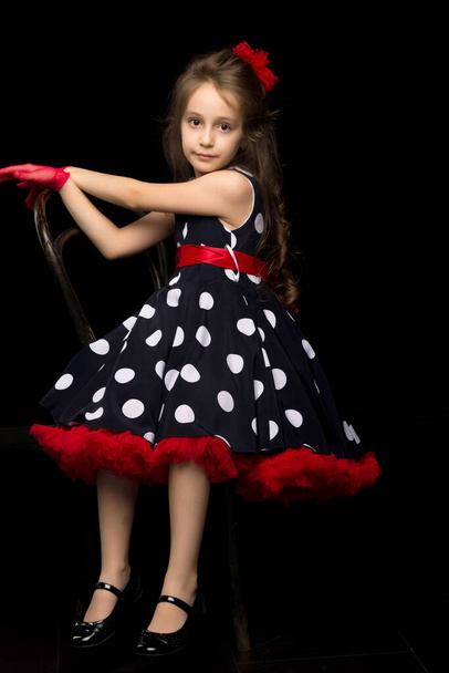 Pretty Girl in Polka Dot Dress Sitting on Isolated Black Background. - Zdjęcie, obraz