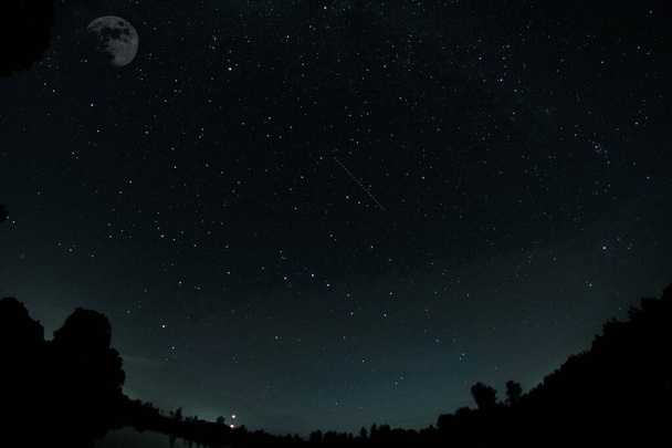 Céu escuro azul com muitas estrelas. Céu noturno sobre paisagem rural. alta paisagem ISO com lente fisheye - Foto, Imagem