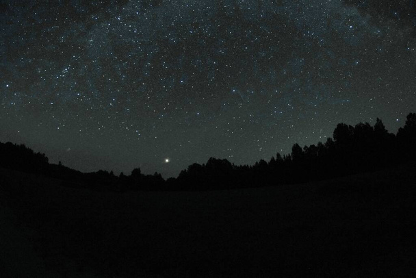 Blauwe donkere nachtelijke hemel met veel sterren. Nachtelijke hemel boven landelijk landschap. hoog ISO landschap met fisheye lens - Foto, afbeelding