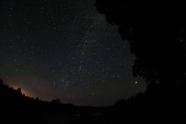 Голубое темное ночное небо со множеством звезд. Ночное небо над сельской местностью. высокий ISO ландшафт с объективом рыбьего глаза - Фото, изображение