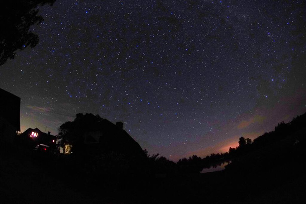 Blauer dunkler Nachthimmel mit vielen Sternen. Nachthimmel über der ländlichen Landschaft. Hohe ISO-Landschaft mit Fischaugenobjektiv - Foto, Bild