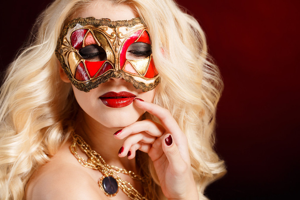 Portrait of a beautiful young blond woman with theatrical mask on his face on a dark background - Photo, Image