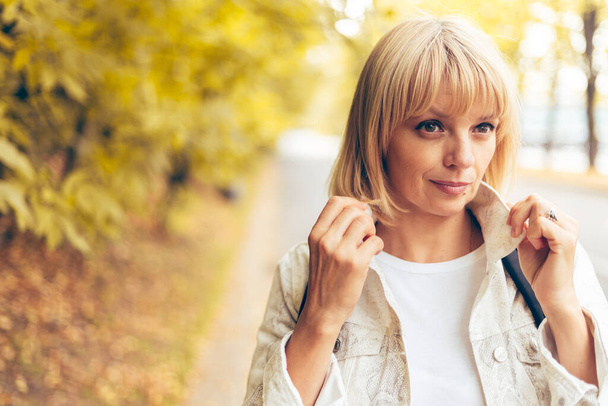 Portrait of beautiful blonde adult woman in the autumn park on the nature walk outdoors. - Φωτογραφία, εικόνα