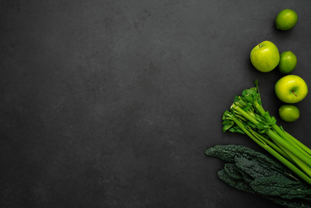 Top view of kale, celery, apples and limes on black background with copy space. Ingredients for green smoothie for breakfast. - Photo, image