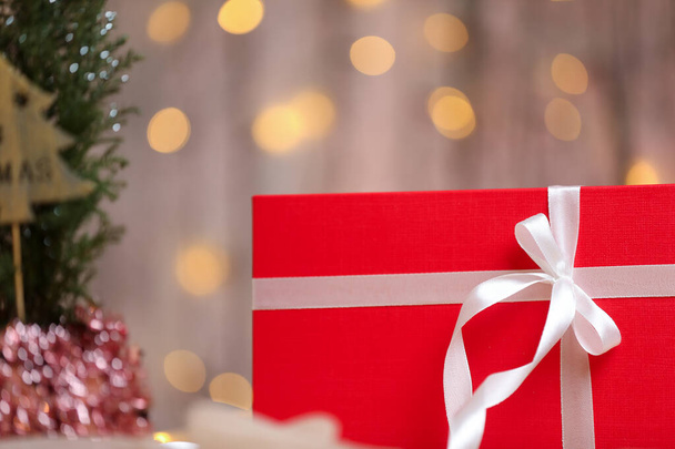 Κόκκινο χριστουγεννιάτικο κουτί δώρου με λευκή κορδέλα σε ένα τραπέζι.  - Φωτογραφία, εικόνα