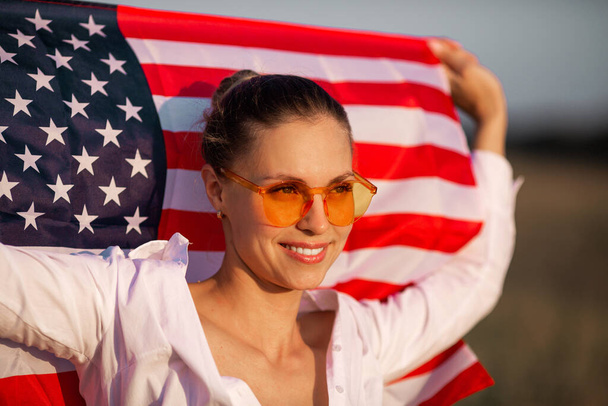 ピンクの眼鏡をかけたアメリカ国旗の美しい若い女性 - 写真・画像