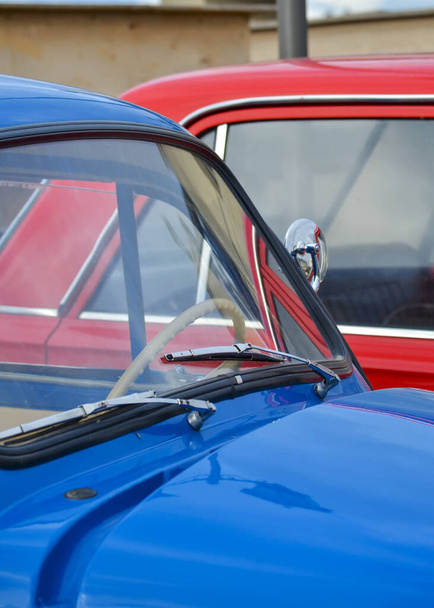 Autó motorháztető és szélvédő egy kék vintage autó a háttérben egy piros autó - Fotó, kép