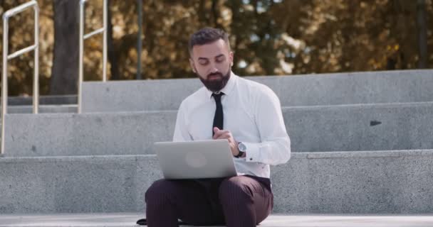 Felice uomo d'affari di mezza età che lavora sul computer portatile e balla sulle scale nel parco autunnale - Filmati, video