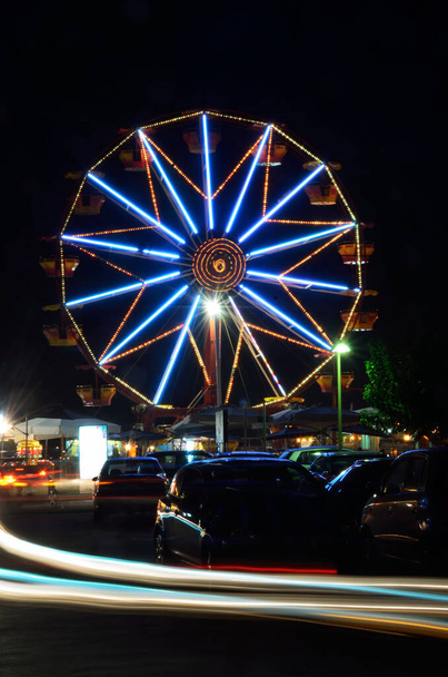 Night view of a Ferris wheel and car trails - Photo, Image