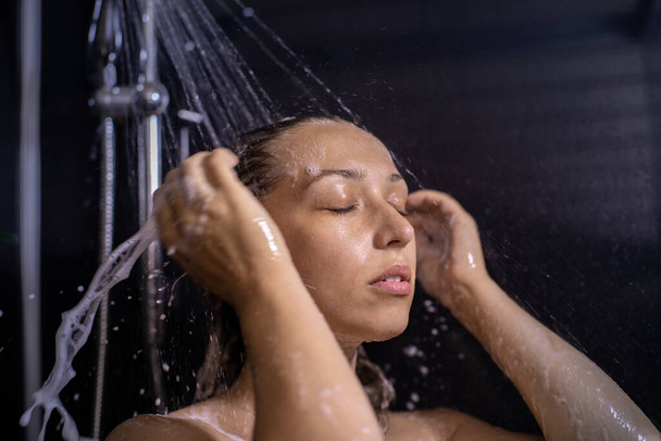 Sakin ve dengeli genç kadın saçı şampuan köpüğüyle duş alıyor. - Fotoğraf, Görsel