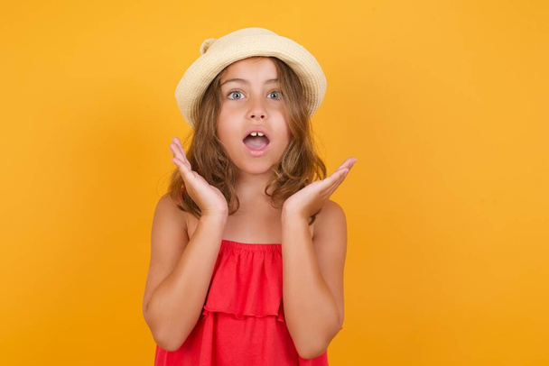 cute little girl wearing red dress is surprised  on yellow background  - Photo, image