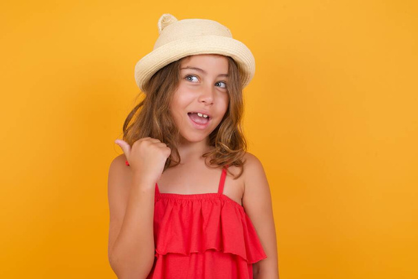 cute little girl wearing red dress showing something  on yellow background  - Photo, Image