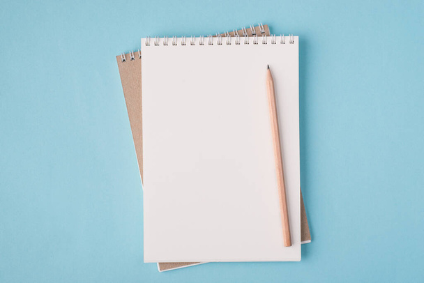 Arriba arriba vista aérea plano laico foto de un cuaderno en blanco y lápiz de madera aislado sobre fondo de color azul pastel con copyspace - Foto, Imagen