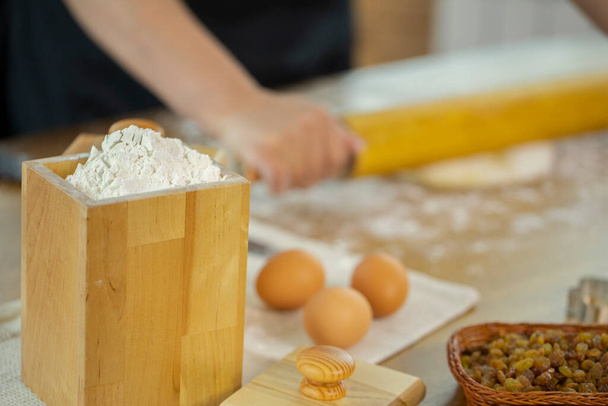 Pšeničná mouka v dřevěné nádobě s vejci na dubovém kuchyňském stole. - Fotografie, Obrázek