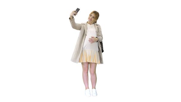 Felice giovane donna incinta prendendo selfie su sfondo bianco. - Foto, immagini