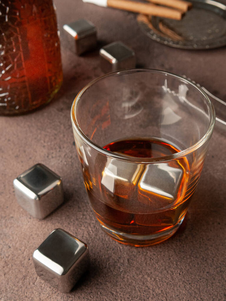 Steel cubes imitating ice. For cooling drinks. With a glass of whiskey. On a brown background. View from above. - Foto, afbeelding